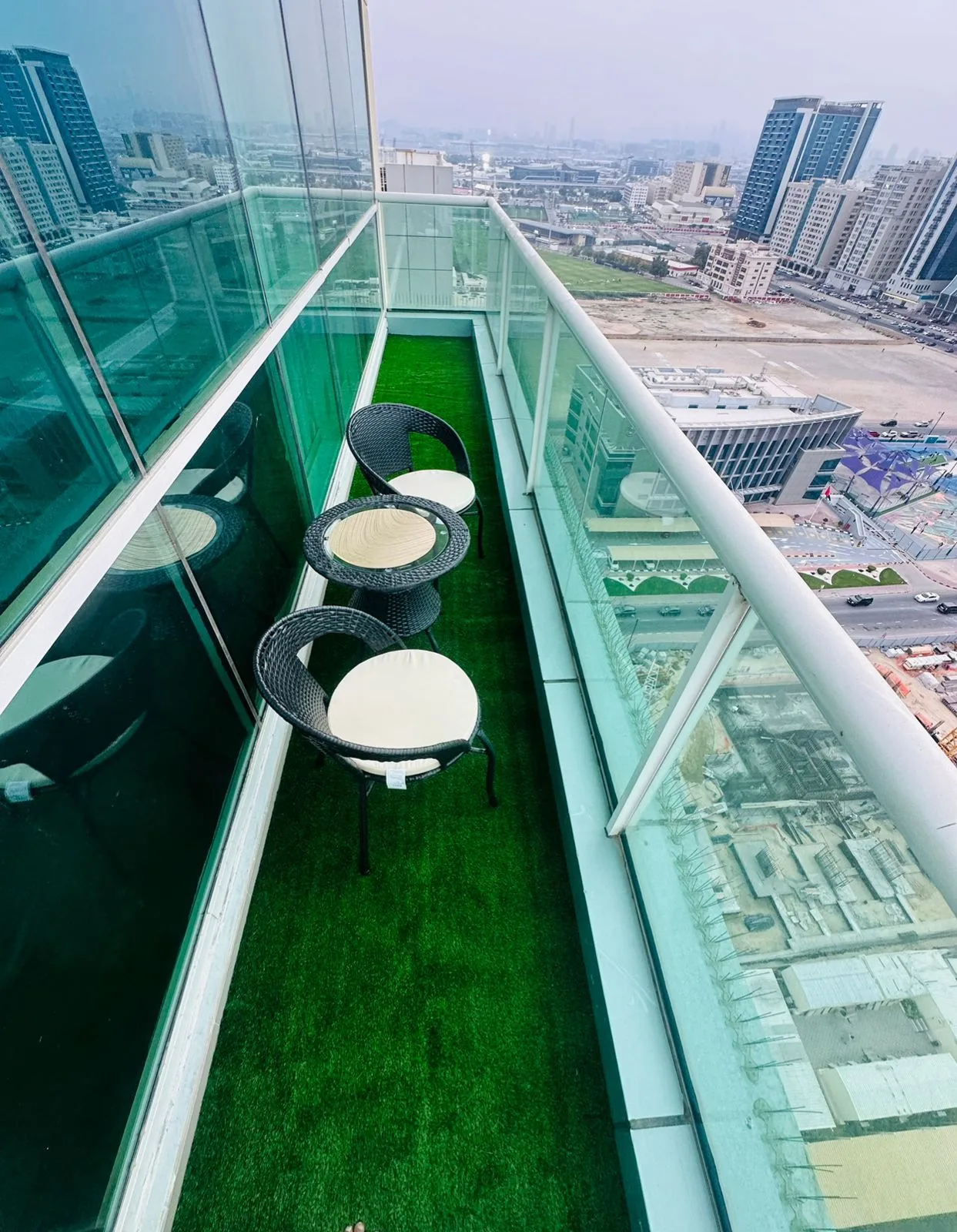 Real Dubai balcony artificial grass installation with rattan chairs