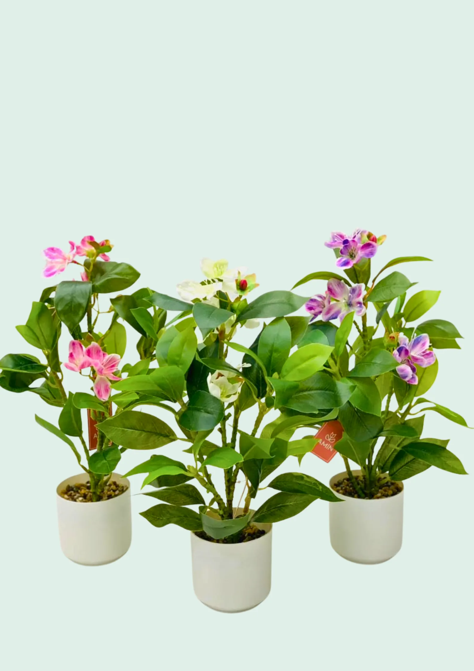 Trio of mini potted artificial flowering plants used for tabletop styling