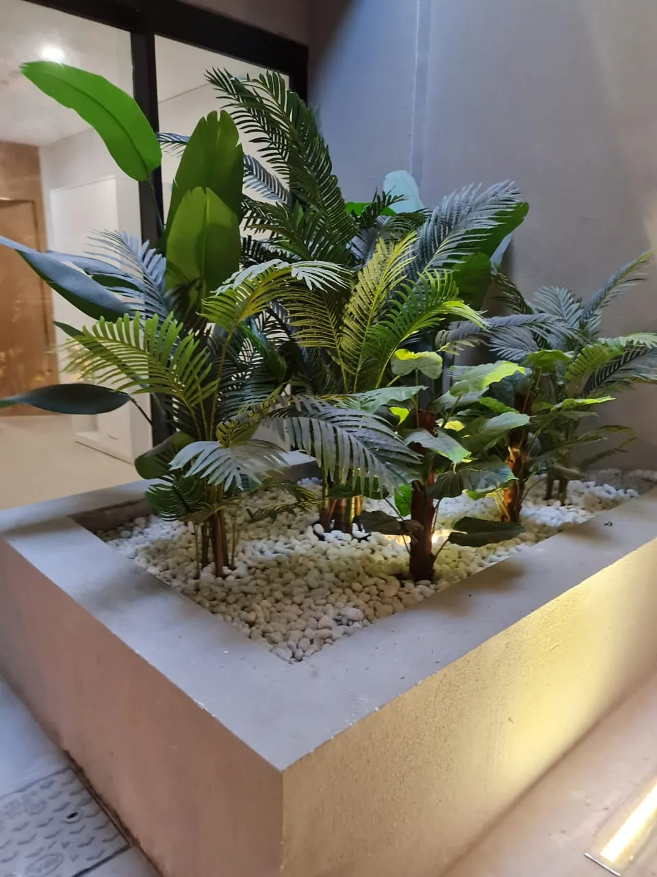 Real completed project: A raised corner planter with palms near the entrance.